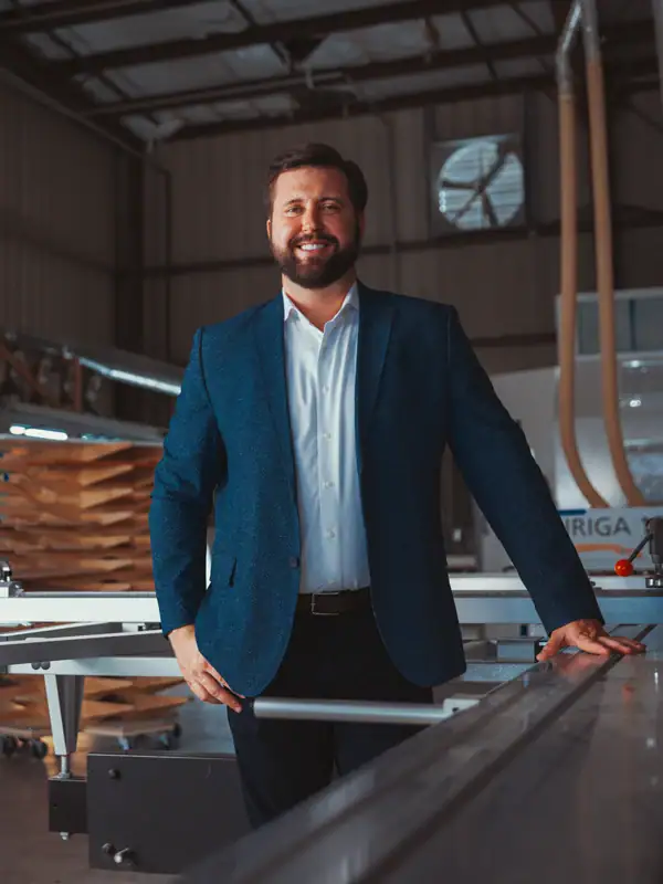 picture of a man smiling standing in front of heavy machinery in a warehouse