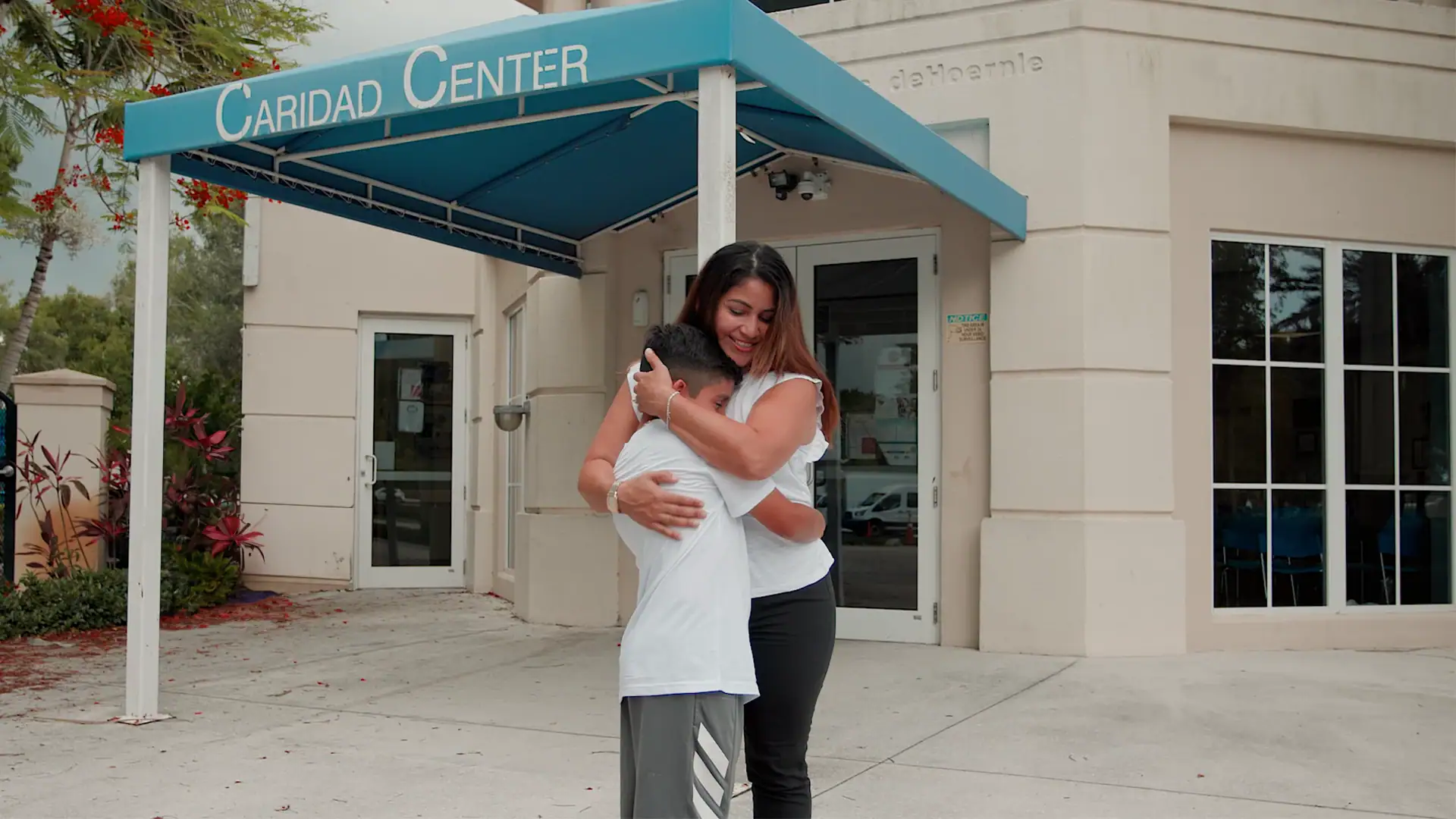 women and child hugging out front of the Caridad building