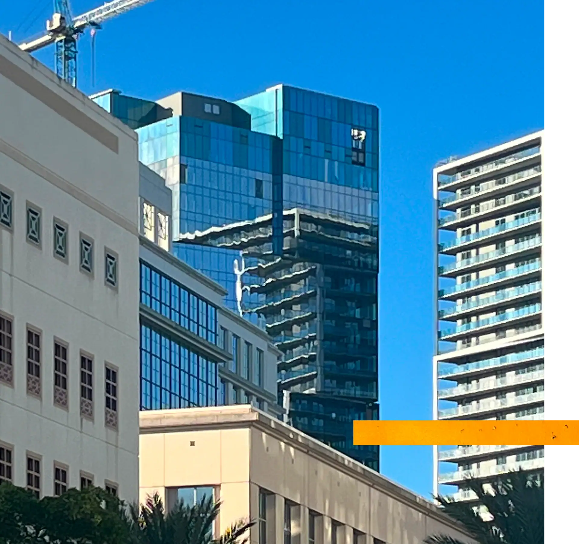 Modern glass skyscrapers reflecting blue sky and surrounding structures.
