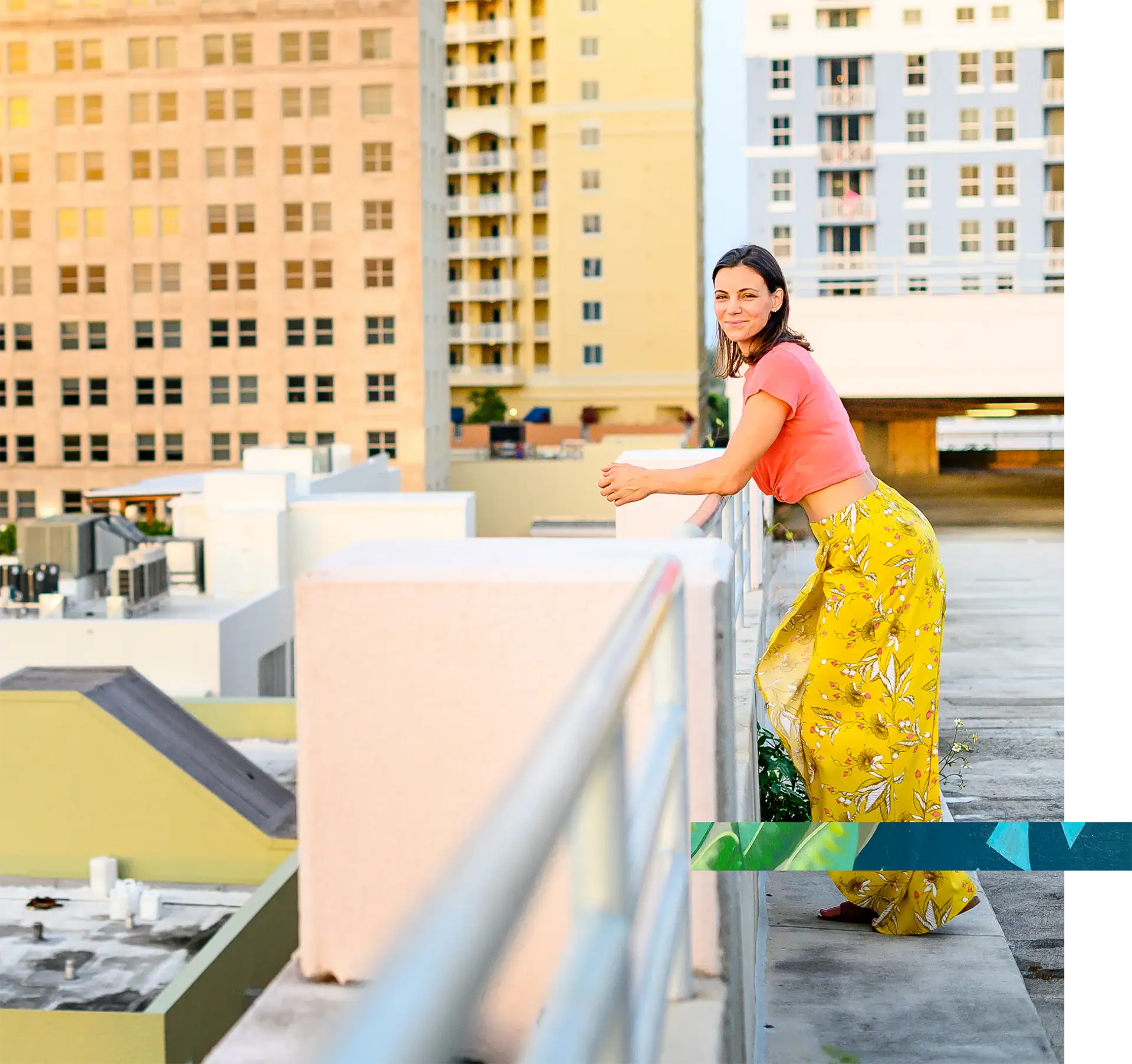 Woman standing on rooftop balcony overlooking city buildings.