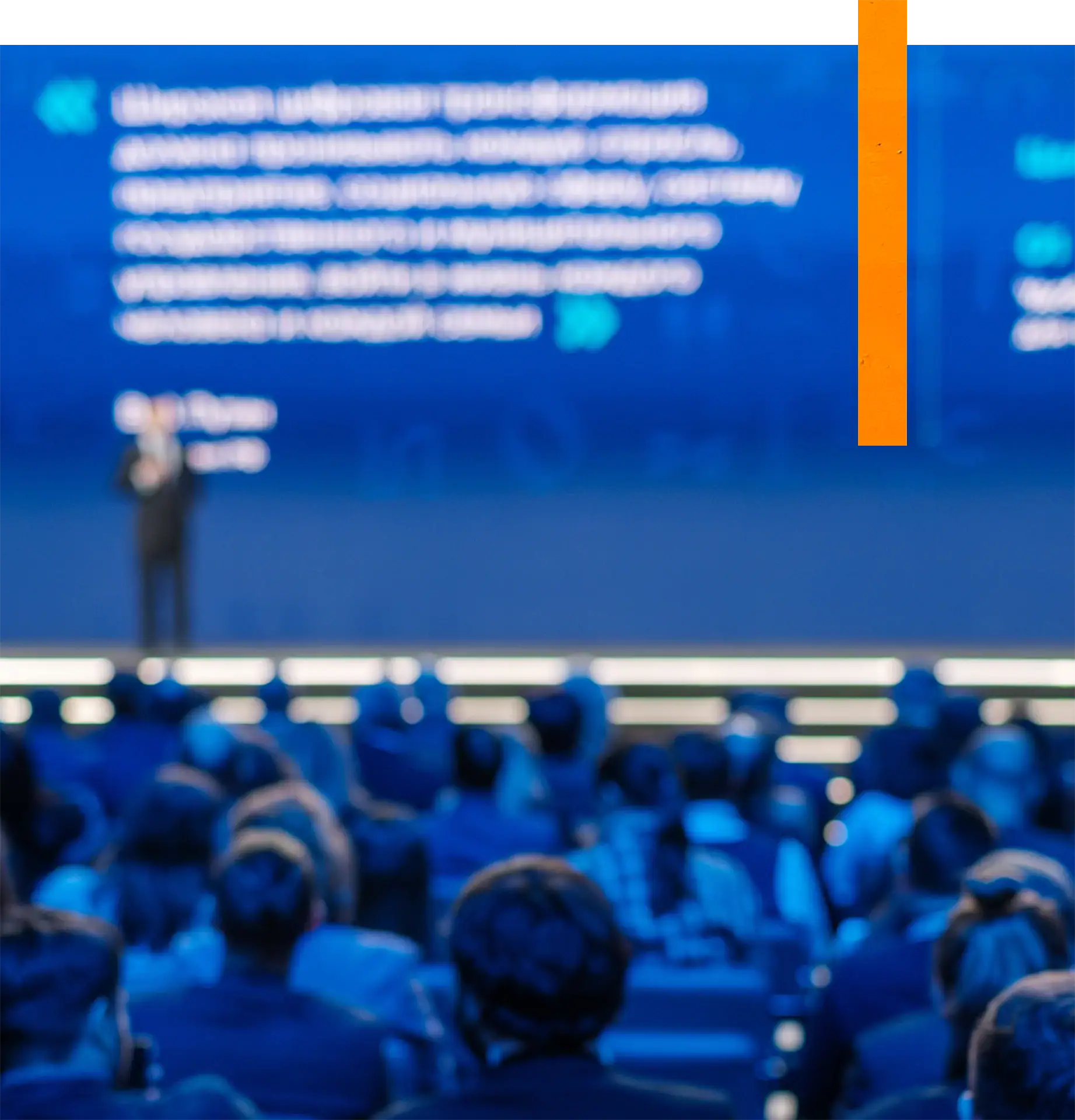 Blurred image of a speaker presenting at a technology conference with an audience.