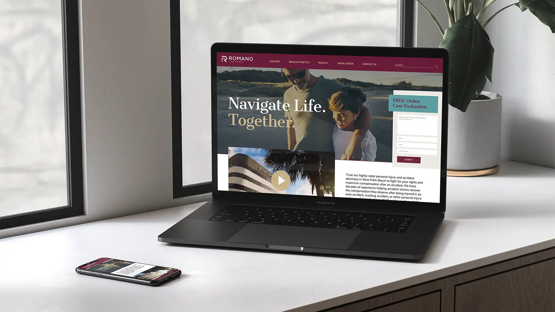 Laptop showing a website homepage with navigation options and a video thumbnail.