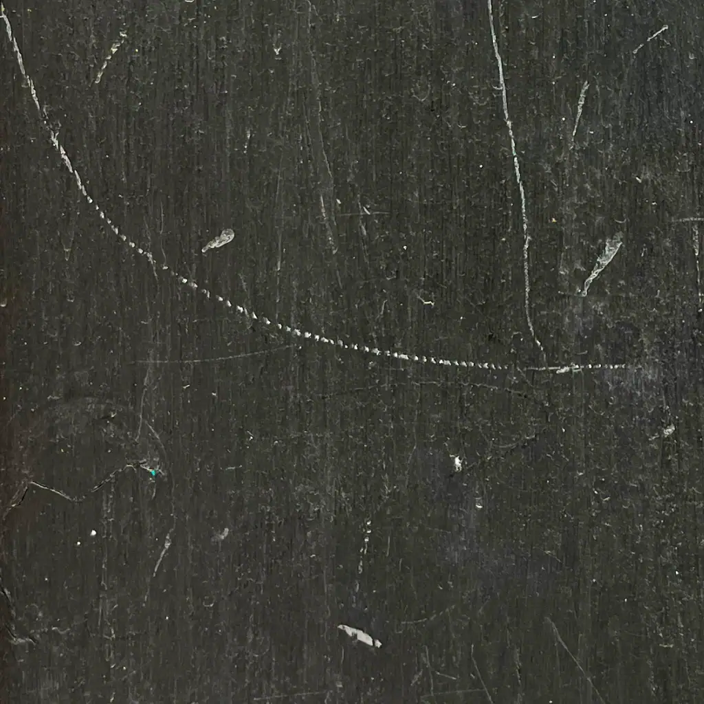 Scratched black surface with cracks and marks, close-up texture.