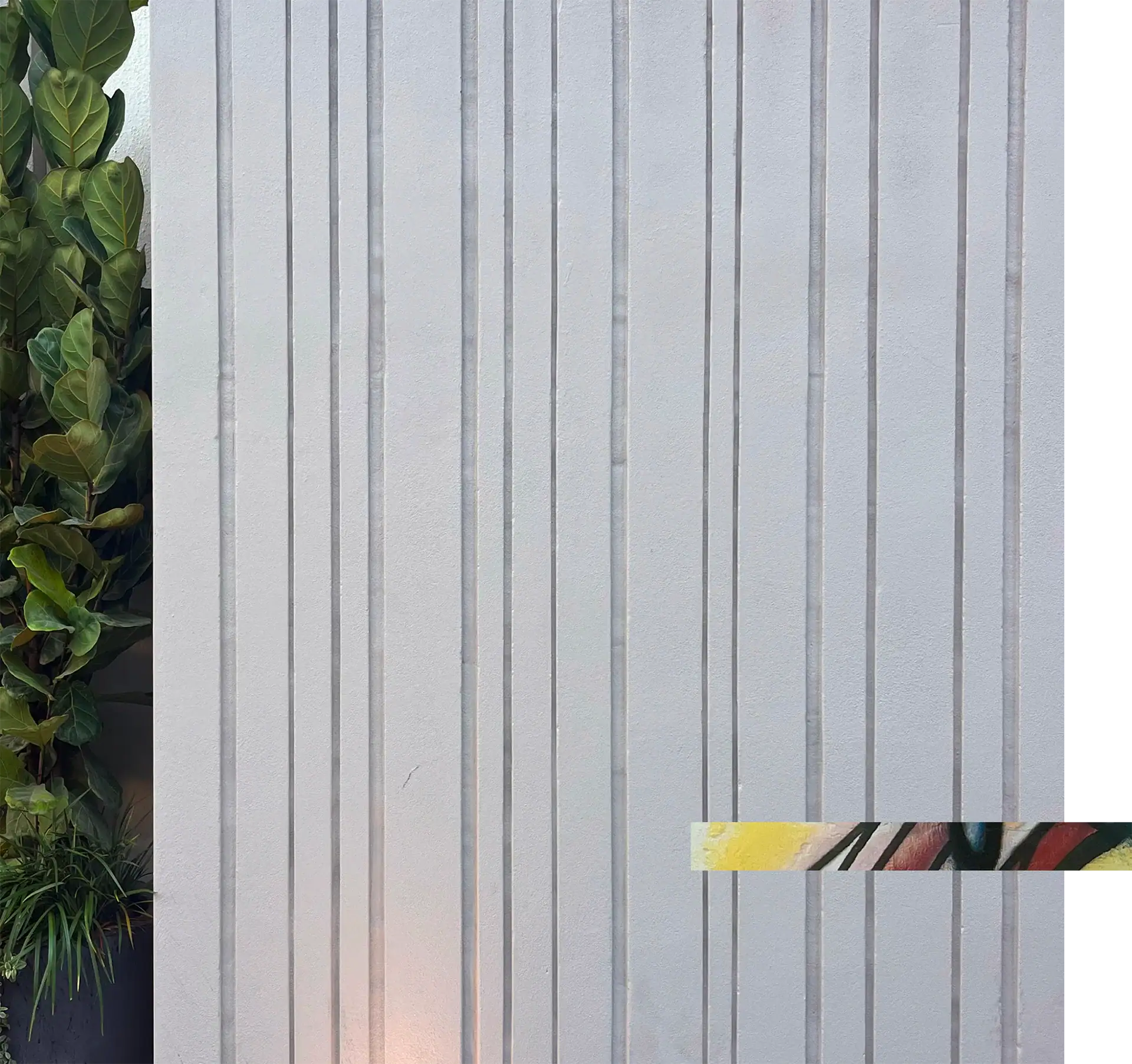 White vertical wooden panel wall with green plants on the side.
