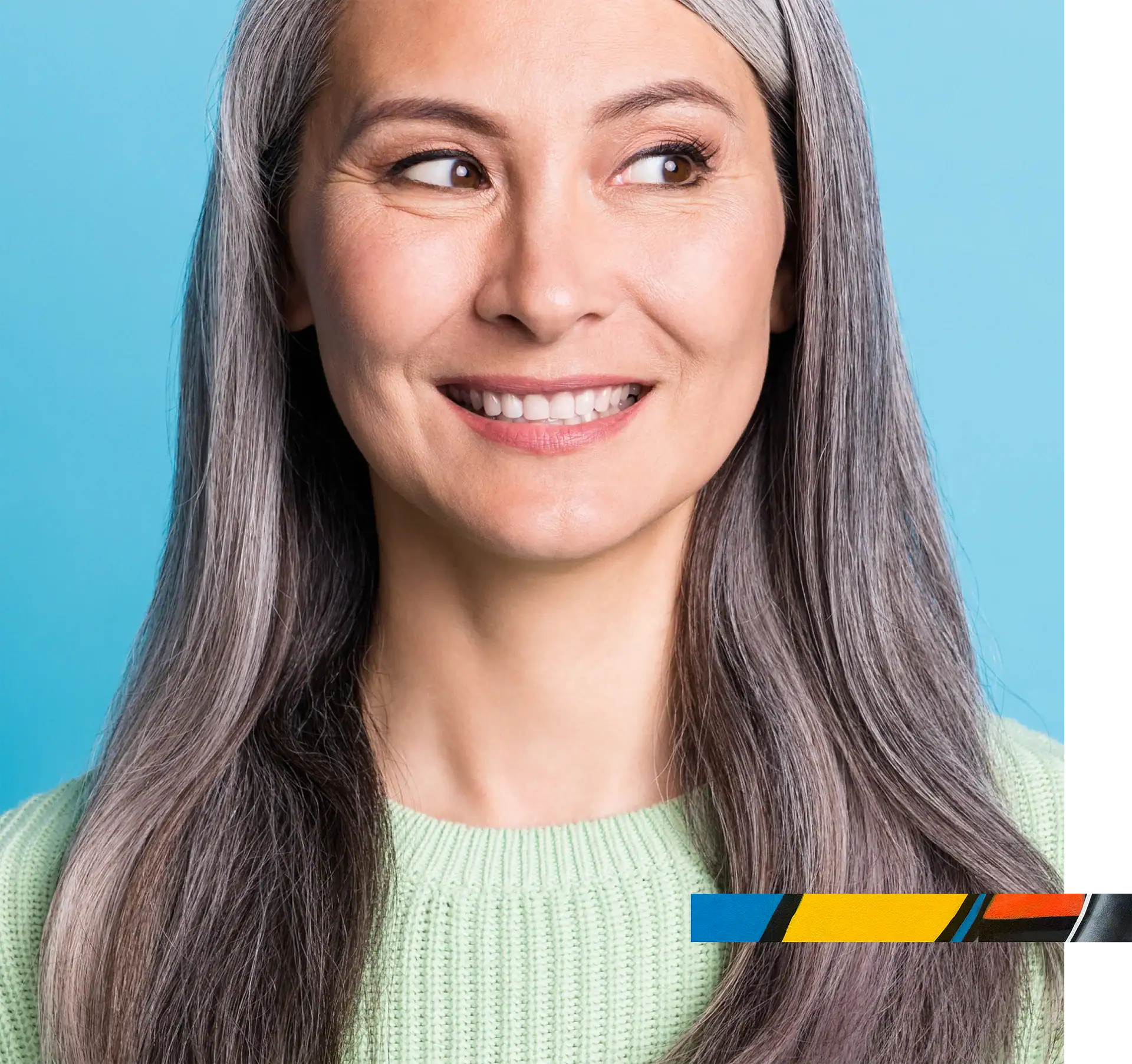 Smiling woman with gray hair and bright expression, wearing a light green sweater, in a professional.