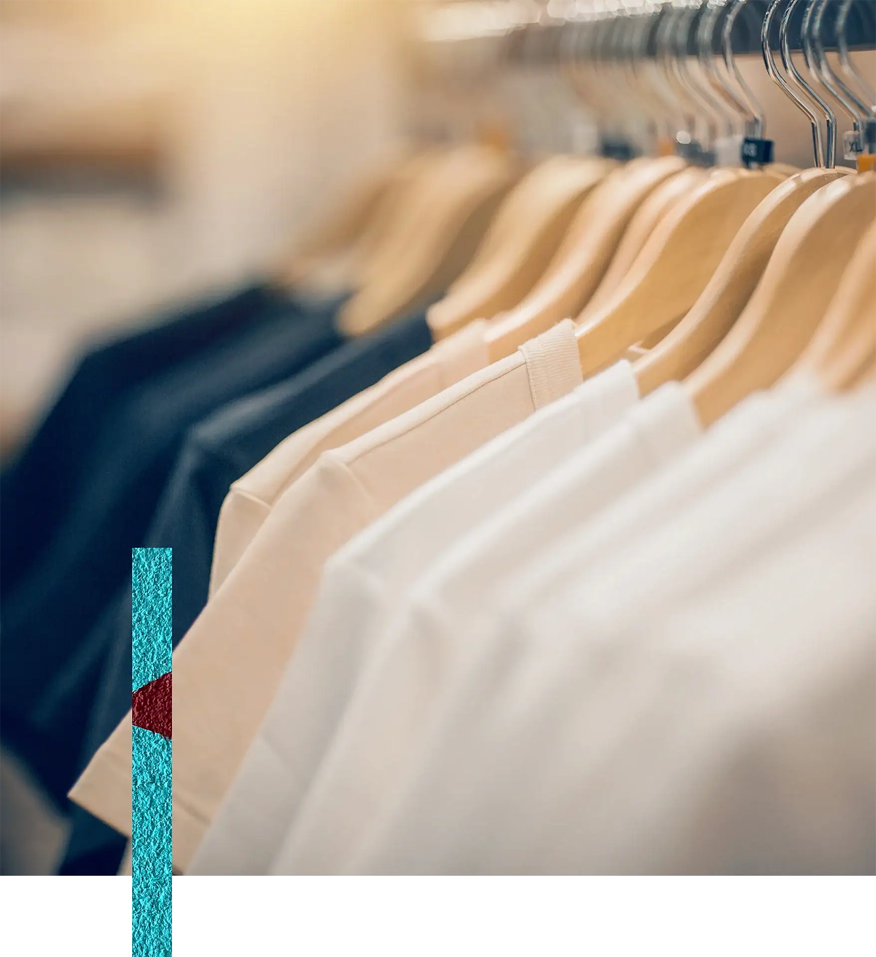 Clothing store display with beige, white, and black T-shirts on wooden hangers.