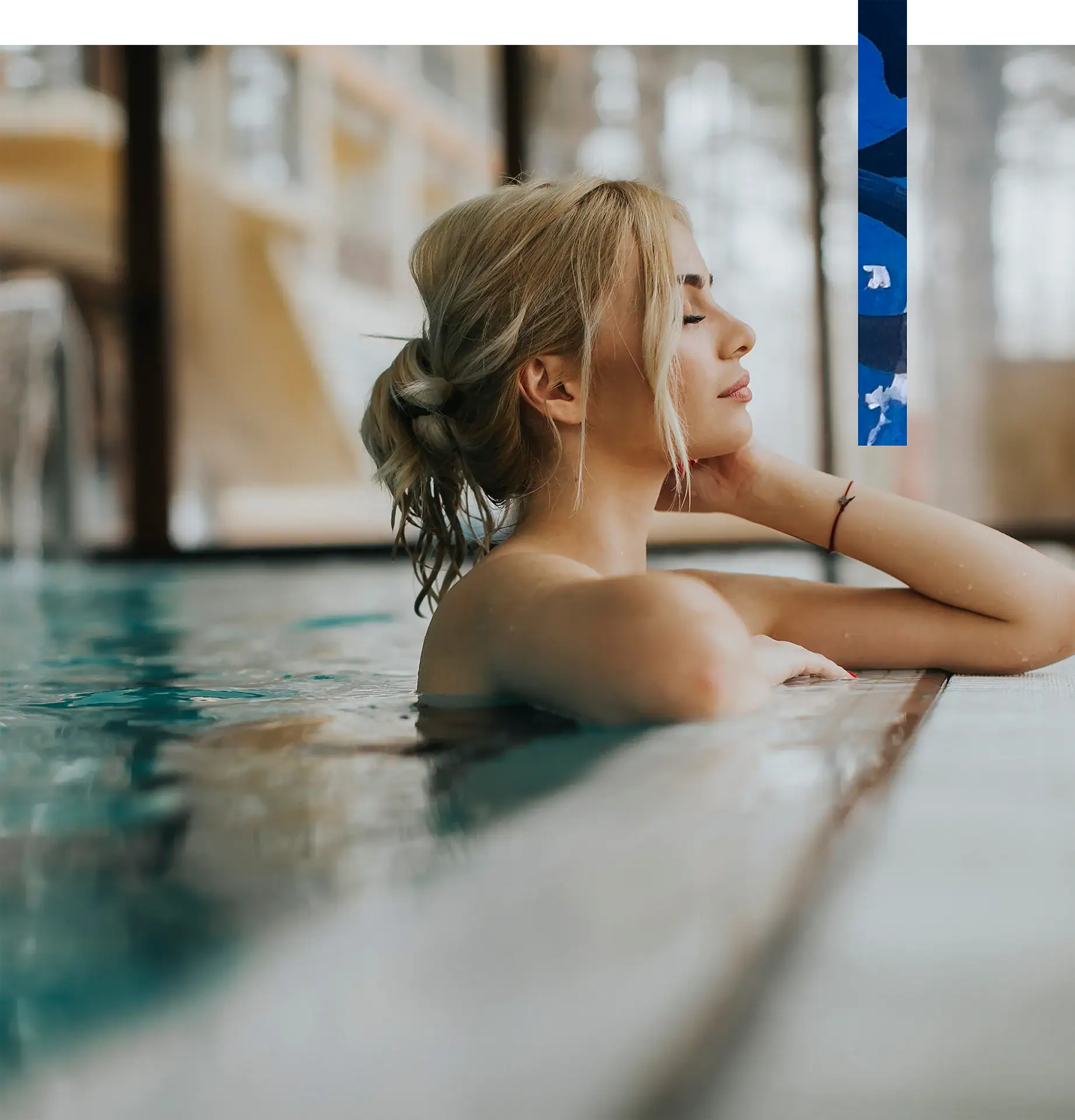 Relaxed woman with blonde hair in a spa pool, enjoying a peaceful moment in a wellness center.