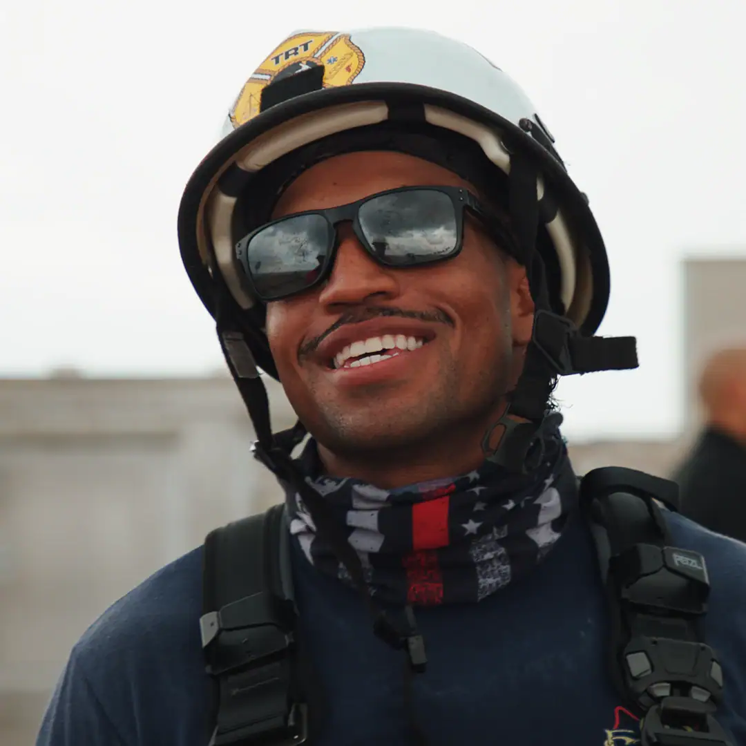 man wearing a firefighter helmet and sunglasses smiling