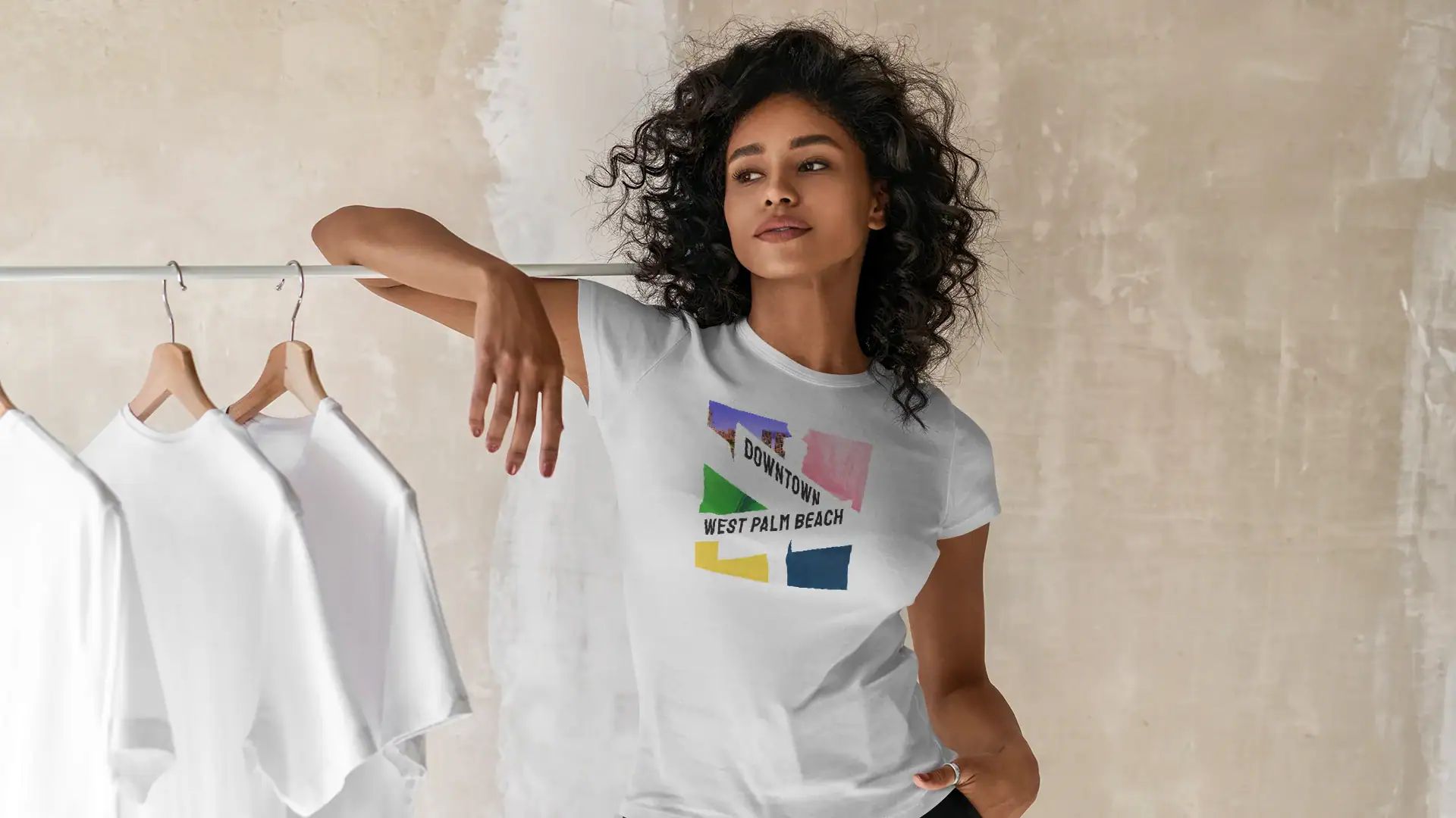 Woman with curly hair wearing a Pathos branded T-shirt in studio.